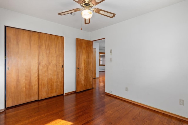 unfurnished bedroom featuring dark wood-type flooring, a closet, and ceiling fan