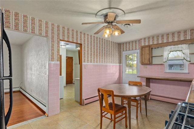 tiled dining room with tile walls, baseboard heating, and ceiling fan