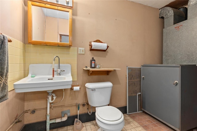 bathroom featuring tile walls, toilet, decorative backsplash, and sink