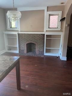 unfurnished living room featuring a fireplace, dark hardwood / wood-style flooring, and a notable chandelier