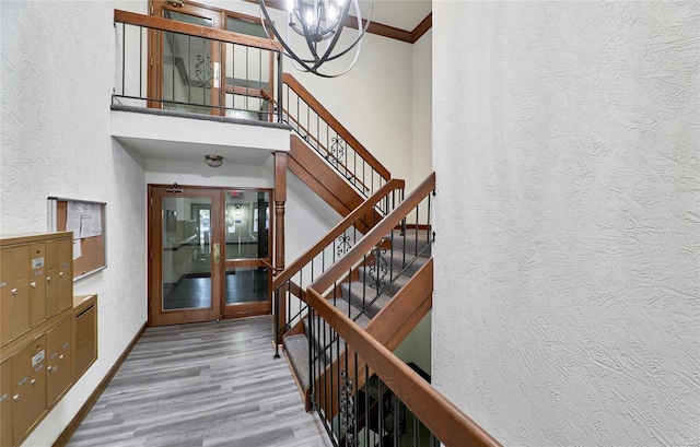 interior space featuring a textured wall, wood finished floors, a towering ceiling, and crown molding