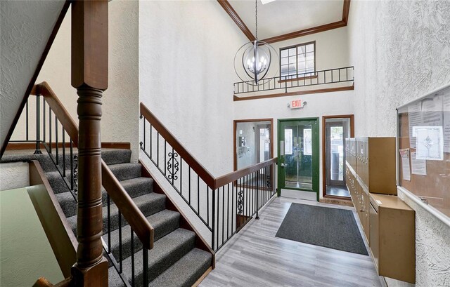 entryway featuring a chandelier, a textured wall, wood finished floors, french doors, and crown molding