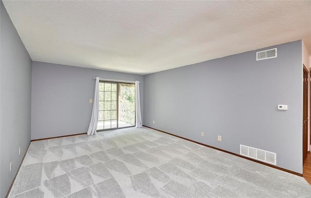 empty room with baseboards, a textured ceiling, visible vents, and light colored carpet