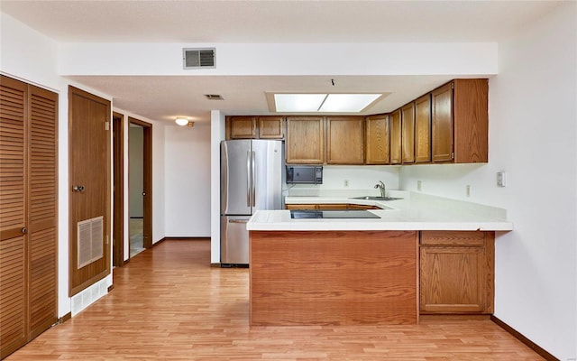 kitchen with black microwave, a peninsula, visible vents, and freestanding refrigerator