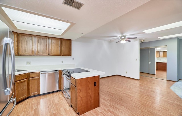 kitchen featuring a skylight, visible vents, appliances with stainless steel finishes, a peninsula, and light wood-style floors