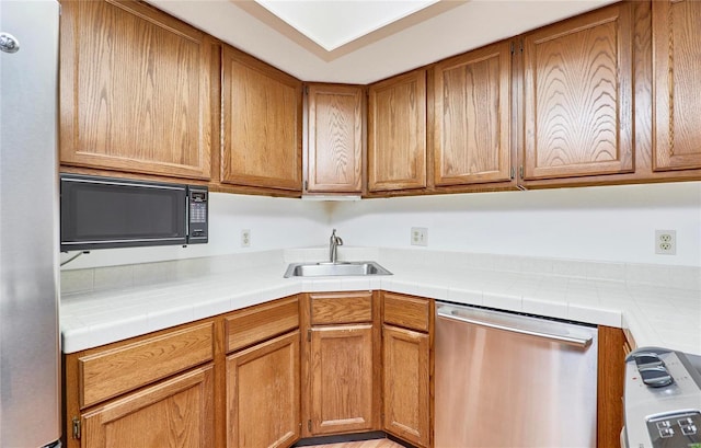 kitchen with black microwave, brown cabinets, a sink, and stainless steel dishwasher