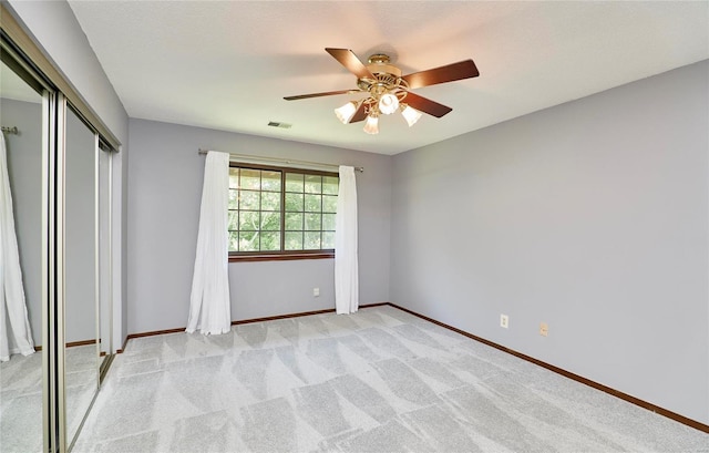 unfurnished bedroom with a closet, visible vents, a ceiling fan, light carpet, and baseboards