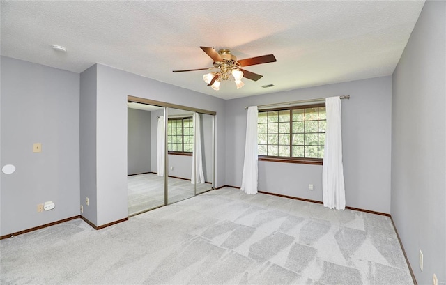 unfurnished bedroom with multiple windows, carpet flooring, visible vents, and baseboards