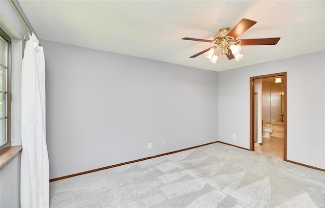 spare room with ceiling fan, baseboards, a textured ceiling, and light colored carpet