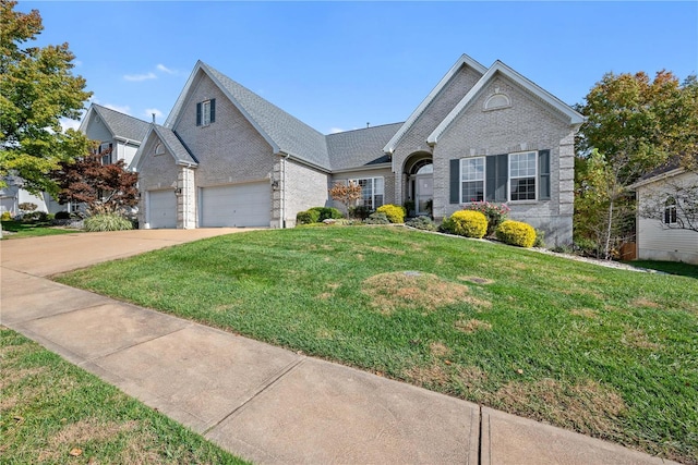 view of front of house with an attached garage, driveway, a front lawn, and brick siding