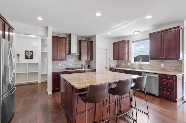 kitchen featuring dark wood-type flooring, a kitchen island, stainless steel appliances, and wall chimney range hood