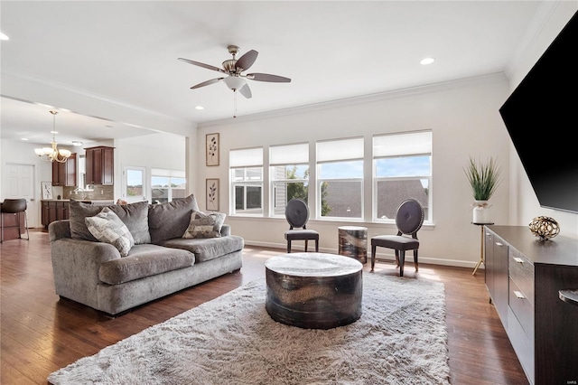 living room featuring ceiling fan with notable chandelier, dark hardwood / wood-style flooring, crown molding, and a healthy amount of sunlight