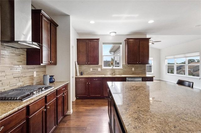 kitchen with dark wood-type flooring, wall chimney range hood, sink, decorative backsplash, and appliances with stainless steel finishes