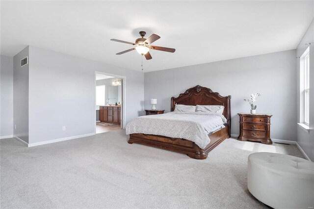 bedroom with ceiling fan, ensuite bathroom, and light colored carpet