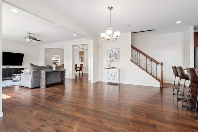 living room with dark hardwood / wood-style floors, crown molding, and ceiling fan with notable chandelier