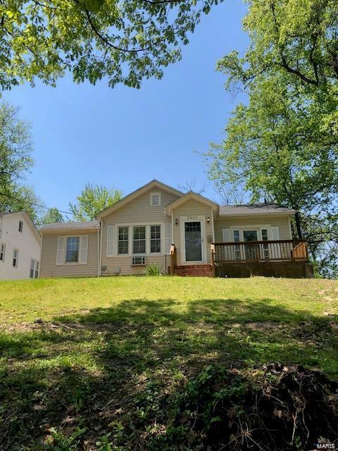 back of house with a wooden deck and a lawn