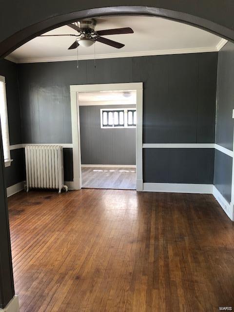 spare room with radiator heating unit, hardwood / wood-style flooring, and ceiling fan