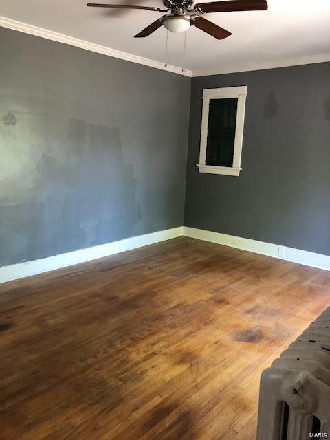 empty room with wood-type flooring, crown molding, and ceiling fan