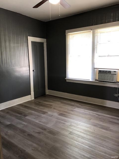 empty room featuring plenty of natural light, ceiling fan, hardwood / wood-style flooring, and cooling unit