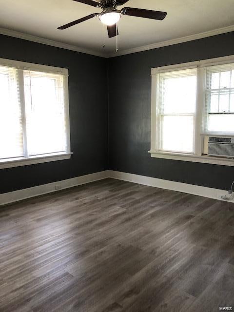 empty room with plenty of natural light, cooling unit, ceiling fan, and hardwood / wood-style floors