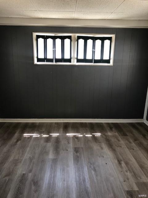 spare room featuring wood-type flooring and a drop ceiling