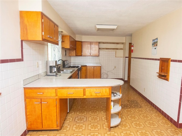 kitchen with tile walls, sink, tasteful backsplash, and kitchen peninsula