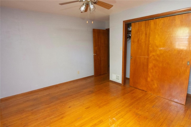 unfurnished bedroom with ceiling fan, hardwood / wood-style flooring, and a closet