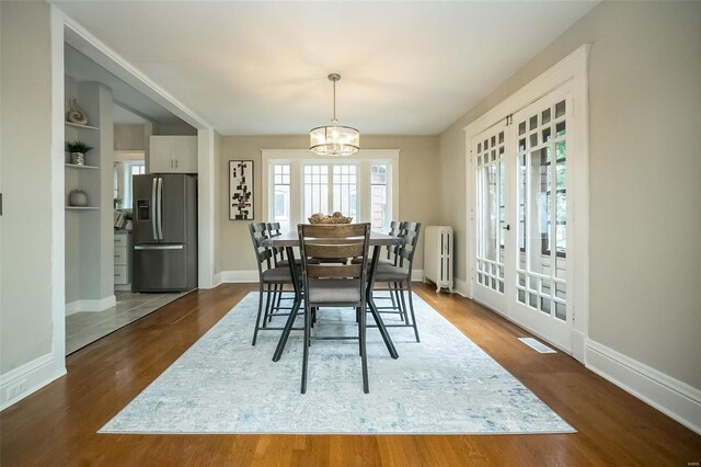 dining space with dark hardwood / wood-style flooring, built in features, radiator, french doors, and a chandelier