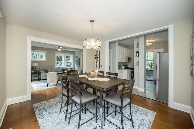 dining area with dark hardwood / wood-style flooring and ceiling fan with notable chandelier