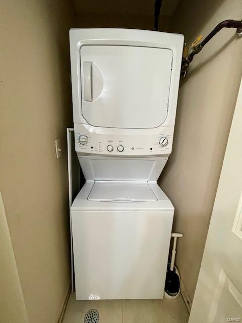 clothes washing area featuring tile patterned floors and stacked washer / drying machine