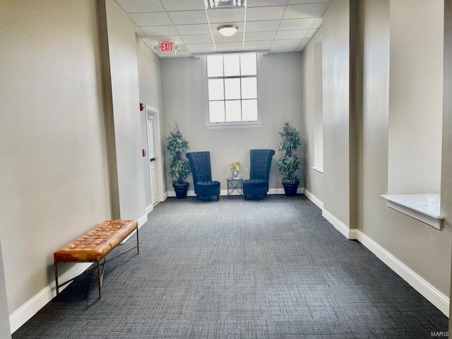 unfurnished room with a paneled ceiling and dark carpet