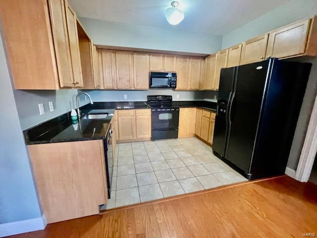 kitchen featuring sink, black appliances, light brown cabinets, and light hardwood / wood-style flooring