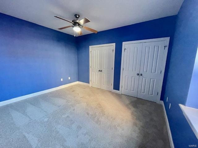 unfurnished bedroom featuring ceiling fan, carpet floors, and multiple closets