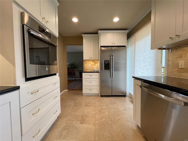 kitchen featuring appliances with stainless steel finishes, backsplash, light tile patterned flooring, and white cabinets