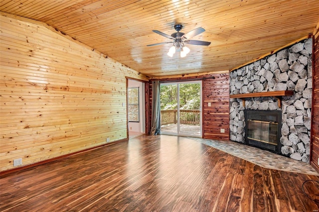 unfurnished living room with wood ceiling, ceiling fan, a stone fireplace, and wood-type flooring