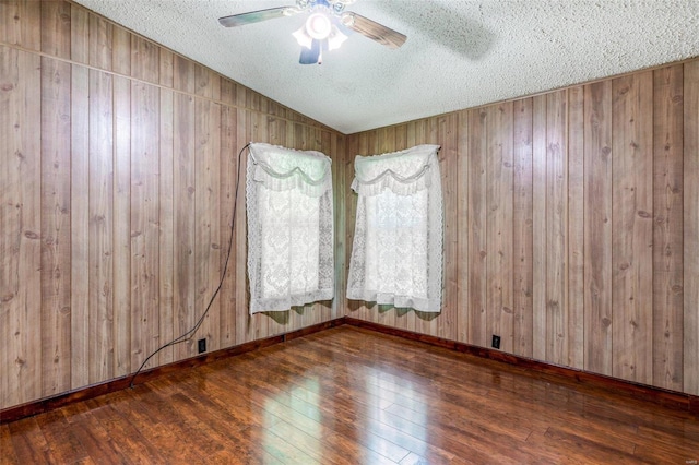 spare room with dark hardwood / wood-style floors, a textured ceiling, and wooden walls