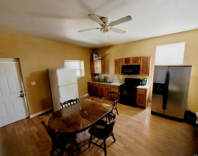 kitchen with brown cabinetry, ceiling fan, black appliances, light countertops, and light wood-style floors