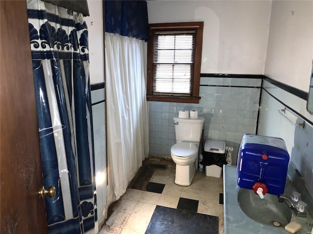 bathroom featuring a wainscoted wall, tile patterned floors, toilet, and a shower with curtain