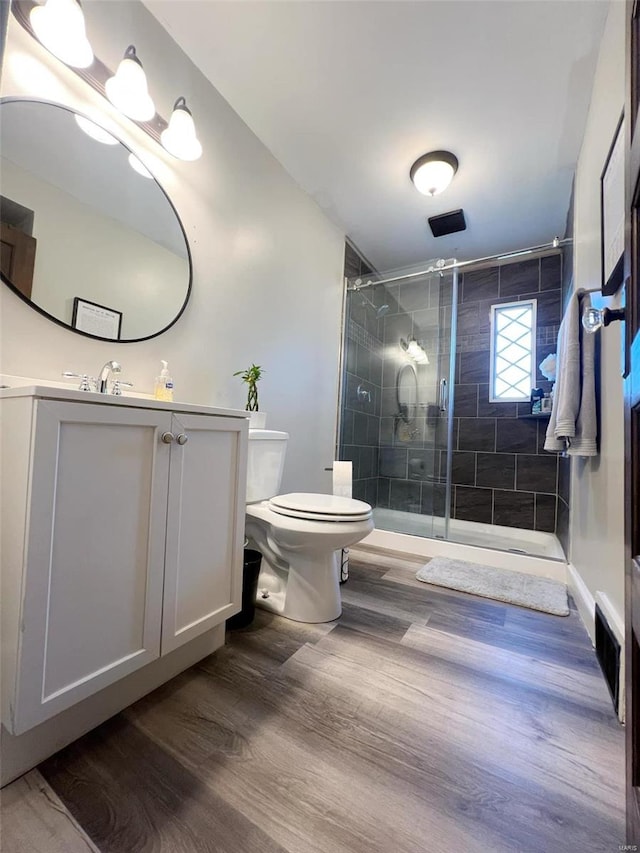 bathroom featuring a shower with shower door, toilet, and wood-type flooring