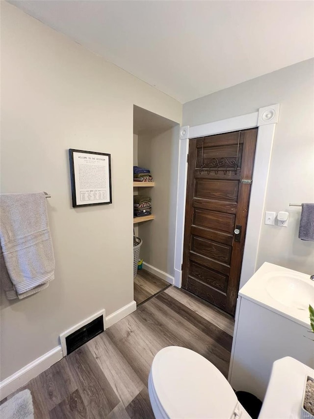 bathroom with toilet, vanity, and hardwood / wood-style flooring