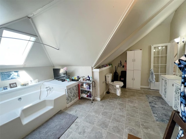 interior space featuring a bathing tub, vaulted ceiling, and toilet