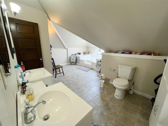 bathroom with vanity, vaulted ceiling, tile patterned flooring, tiled bath, and toilet