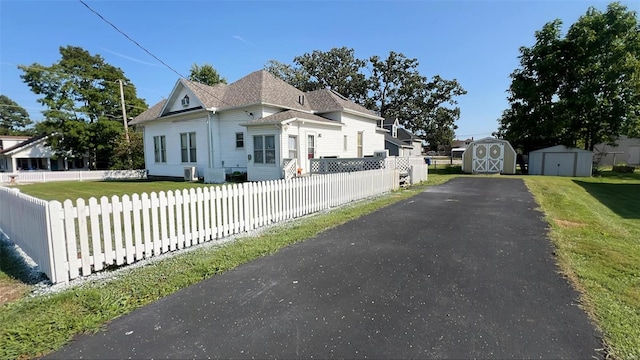 view of front of house with a shed and a front lawn