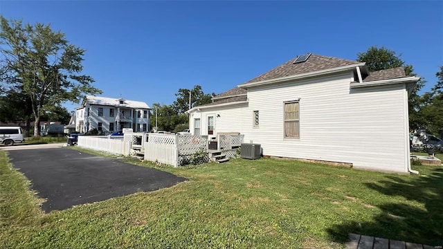 view of side of property featuring central AC unit, a deck, and a lawn