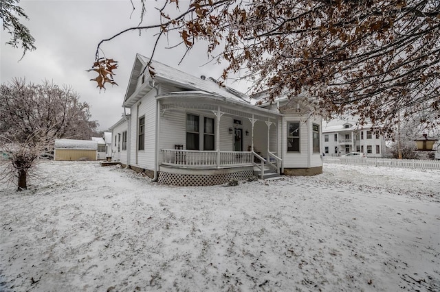 snow covered back of property featuring a porch