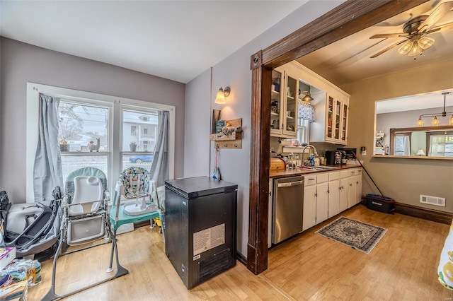 kitchen with sink, light hardwood / wood-style flooring, stainless steel dishwasher, and white cabinets