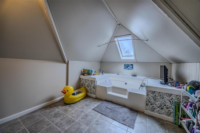 bathroom with vaulted ceiling with skylight and a bathing tub