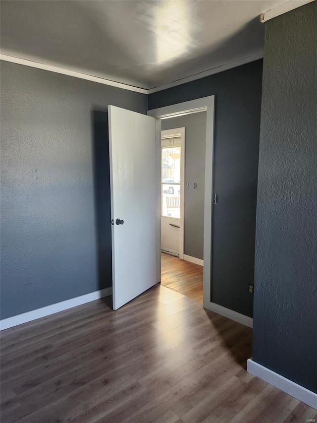 spare room with a textured wall, wood finished floors, and baseboards