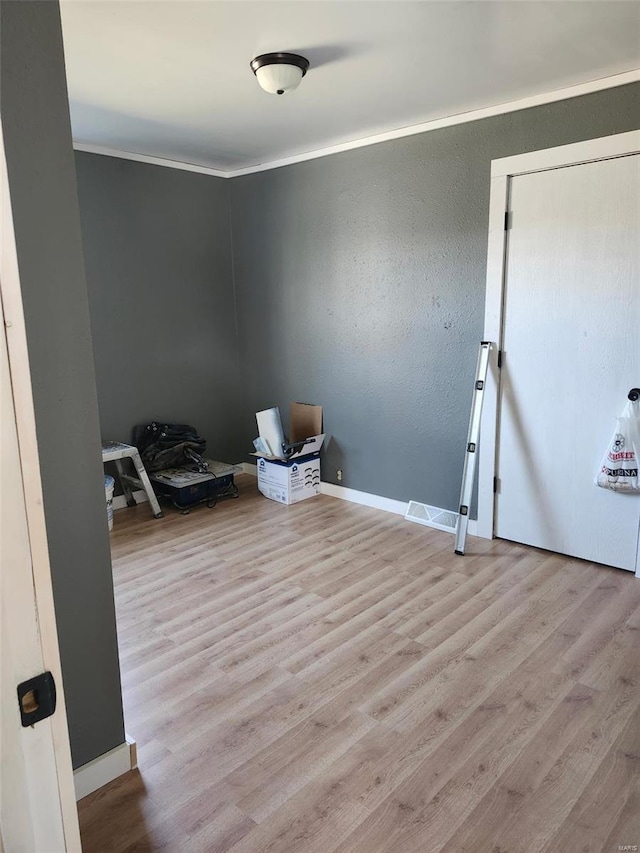 empty room with a textured wall, crown molding, baseboards, and wood finished floors