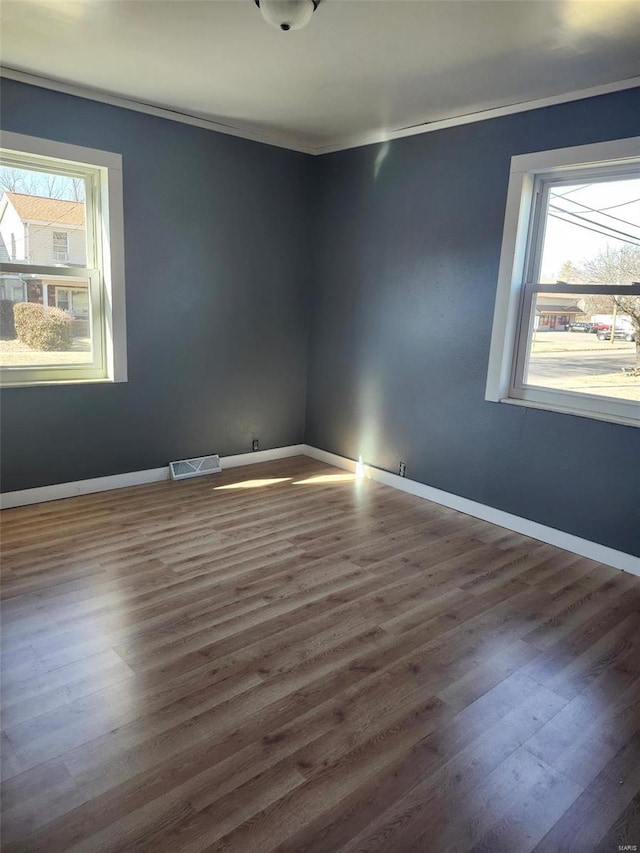 unfurnished room featuring ornamental molding, visible vents, plenty of natural light, and wood finished floors